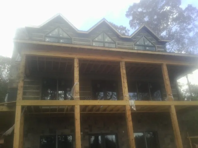 Dormers and porch framing on a large log home under construction — Roof Coating work by our crew in Salamanca