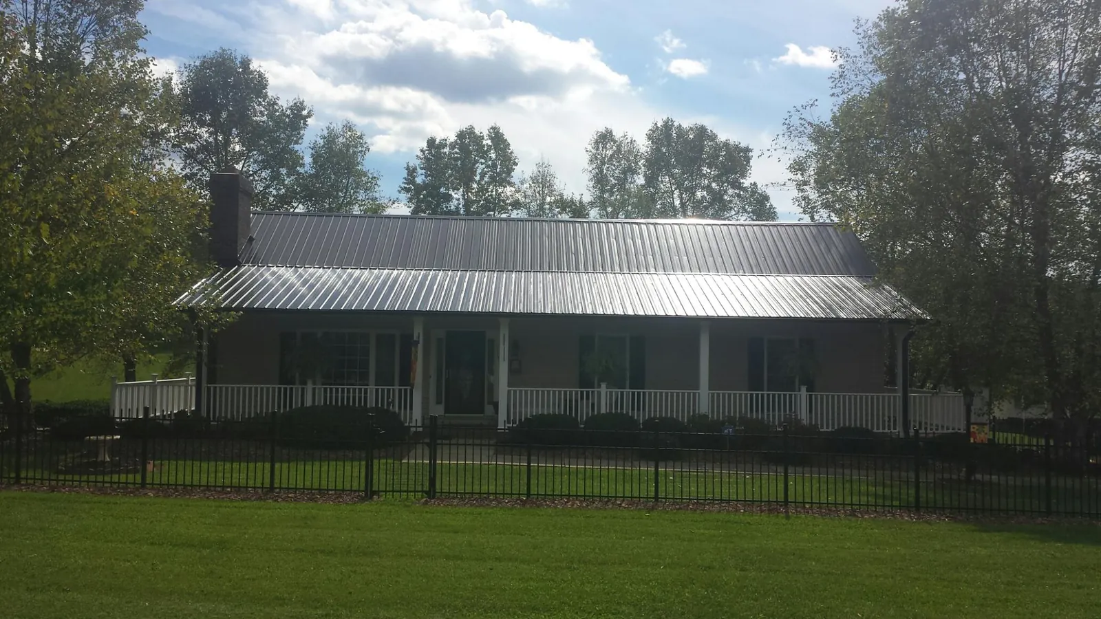 Gray metal roof on a brick ranch with a full width front porch — Gutter Guard Installation work by our crew in Salamanca