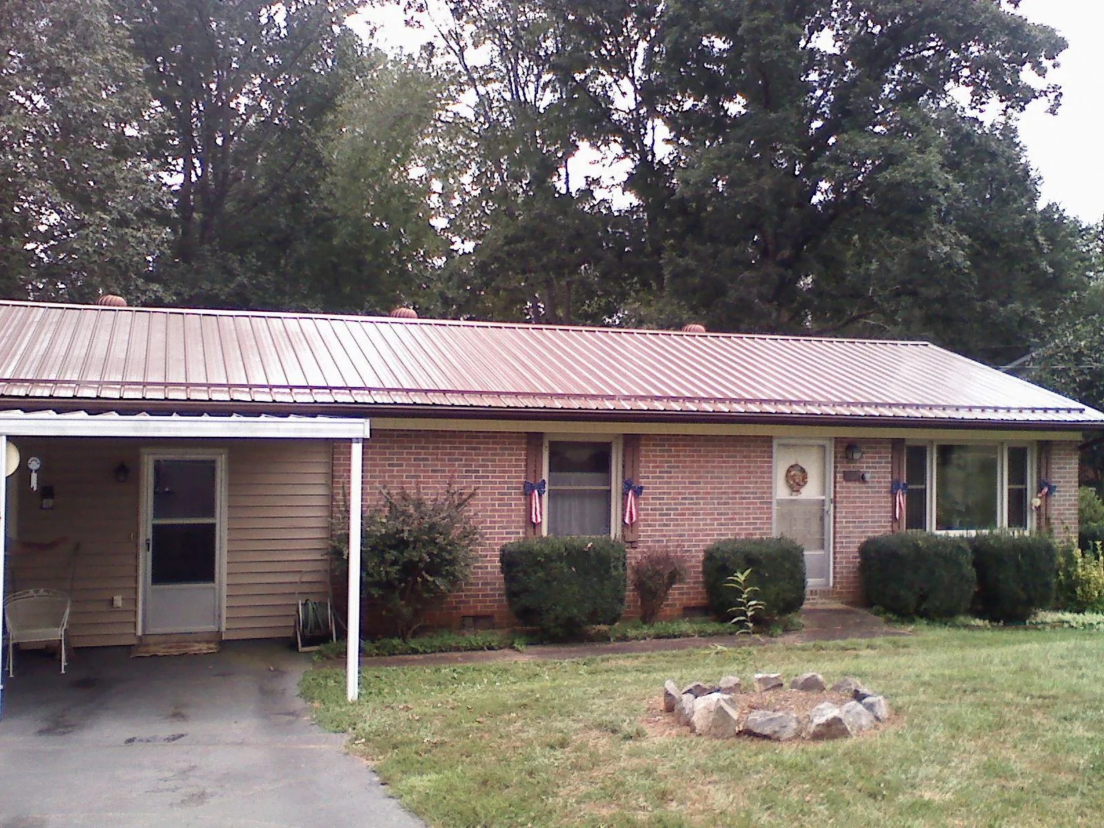 Bronze metal roof and carport on a brick ranch home — Roof Repair work by our crew in Salamanca