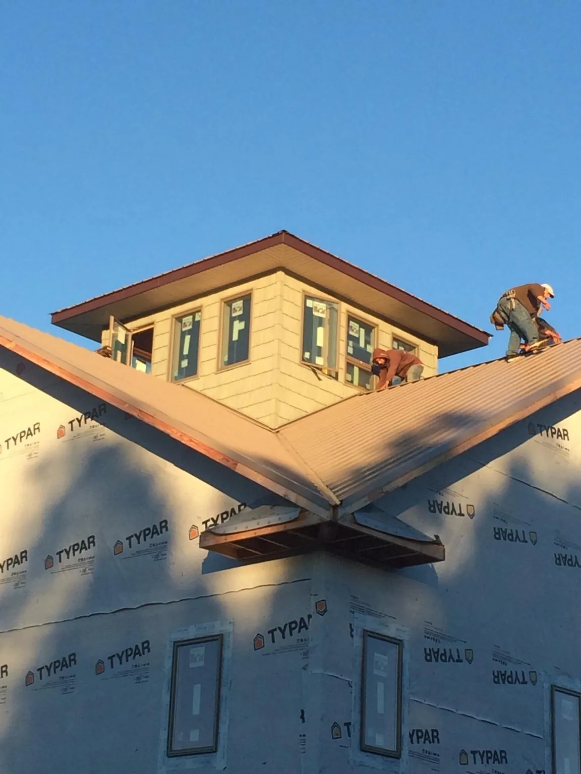 Roofers working around a rooftop cupola on a new metal roof at sunset — Roof Waterproofing in Salamanca by Roofing Brothers
